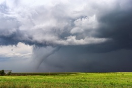 Tornado beneath a supercell thunderstorm over a field.