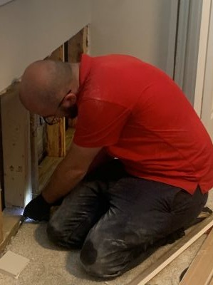 Restoration technician repairing exposed wall framing inside a home.
