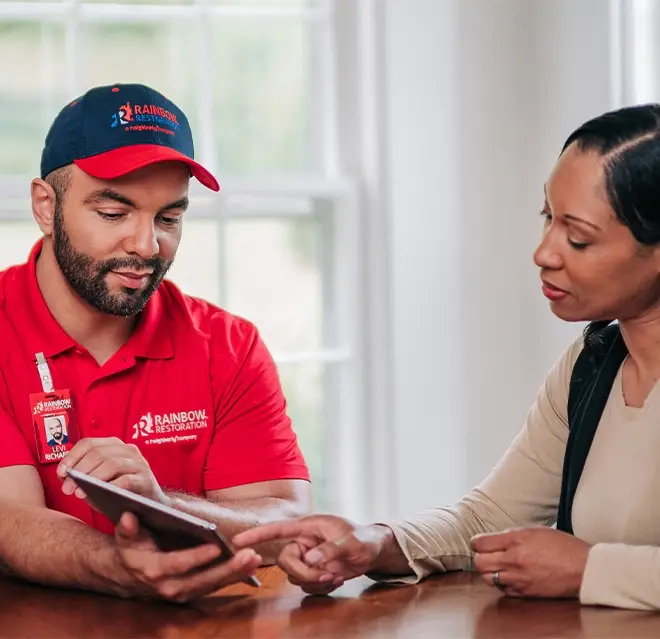 A Rainbow Restoration representative discusses property restoration services with a homeowner in Mandeville, LA.