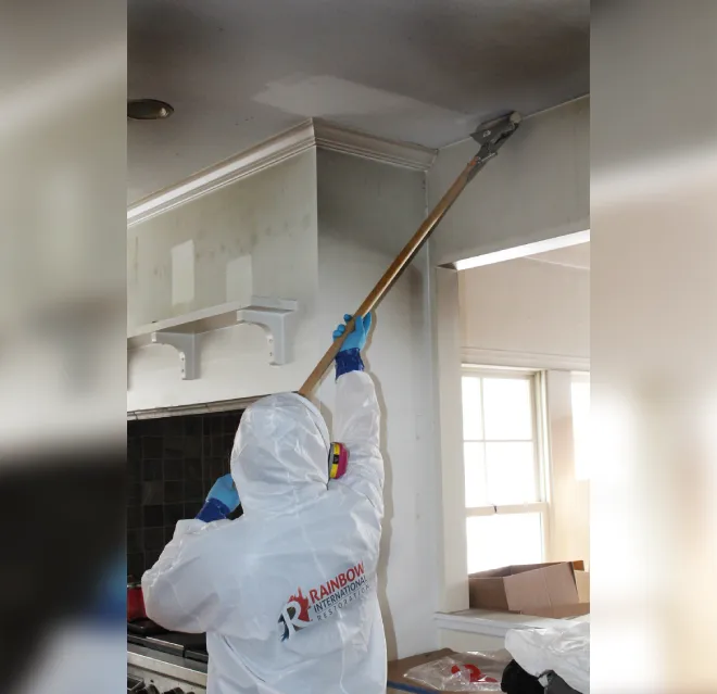 A Rainbow Restoration service professional cleaning smoke damage from a ceiling of a client's kitchen.