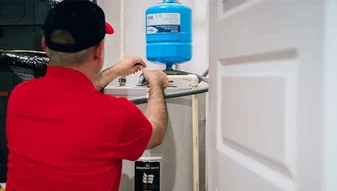 A Rainbow Restoration expert checks for water damage near a water heater at a Liverpool, TX, home.