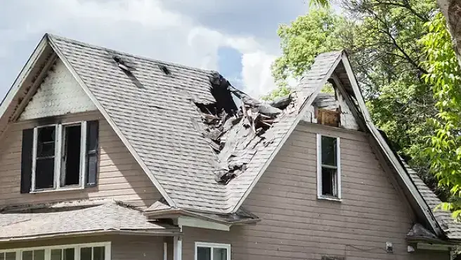 A two-story home with part of the roof caved in due to fire damage.