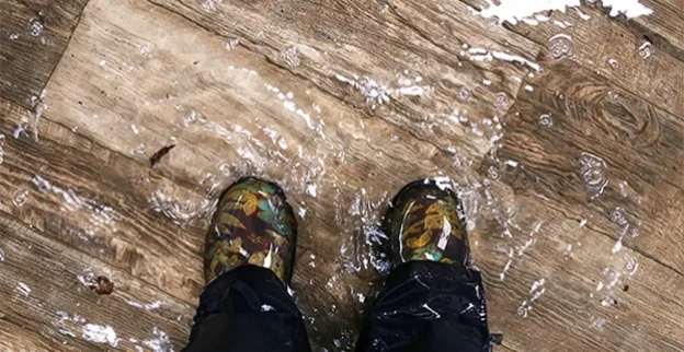 The shoes of a homeowner in need of emergency water damage restoration services standing in water covering the floor of their home in Inman, SC.