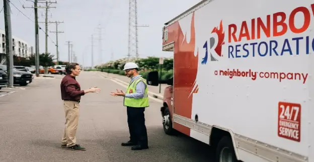 Rainbow Restoration specialist talking to a customer in the street.