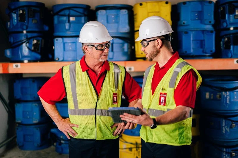 Two Rainbow Restoration specialists discussing equipment they need for a commercial job. 