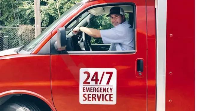 A Rainbow Restoration service professional putting on shoe coverings at a customer's front door next to a branded company mat and briefcase.