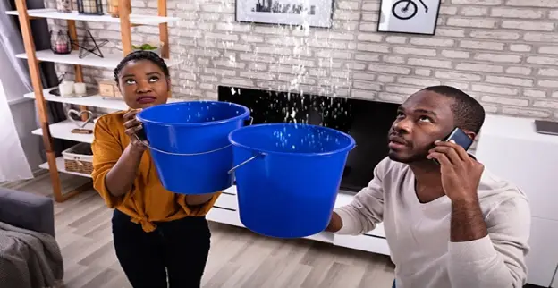 A couple in Greer, SC, calls for help for water damage as water falls from the ceiling and they collect it in buckets.