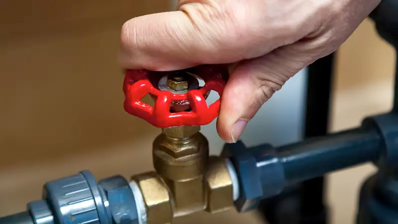 Hand turns off main water shut-off valve.
