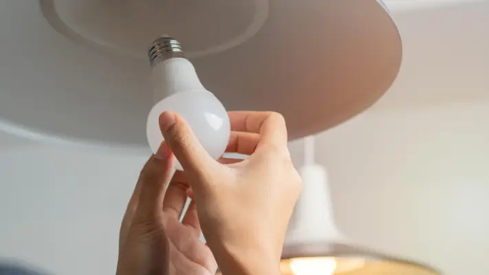 A person examining their flickering light bulbs.