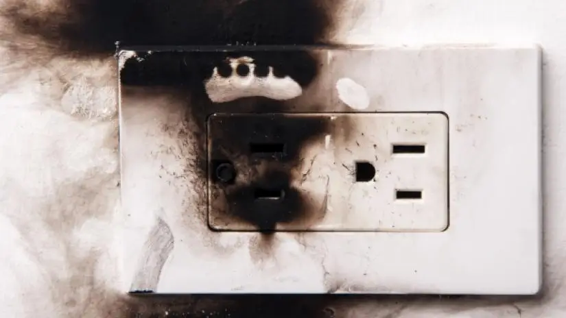 Charred electrical outlet with black smoke damage.