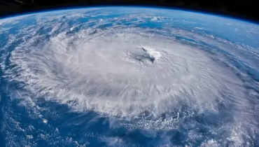 A hurricane over an ocean, seen from space with earth’s horizon in the background.