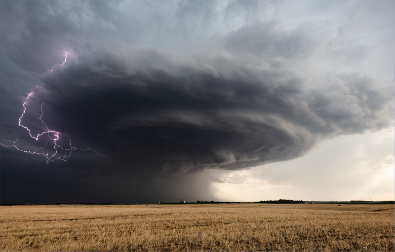 A wall cloud preceding a tornado sweeping across a field.