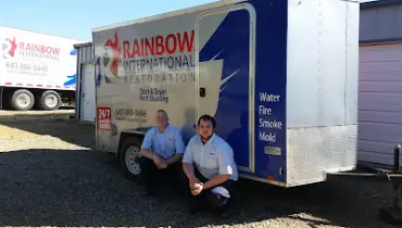 Two technicians sitting in front of rainbow van.