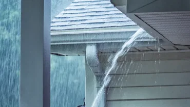 Heavy rain pours from an overflowing roof gutter beside a Chattanooga home during severe weather.