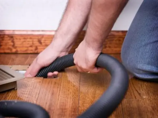 A Rainbow Restoration service professional cleaning an HVAC floor vent to remove dust and allergens and improve indoor air quality in a Jonesborough property.