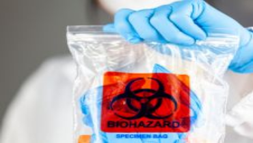Gloved hand holding a sealed biohazard specimen bag, symbolizing professional biohazard cleanup and safe handling of hazardous materials.