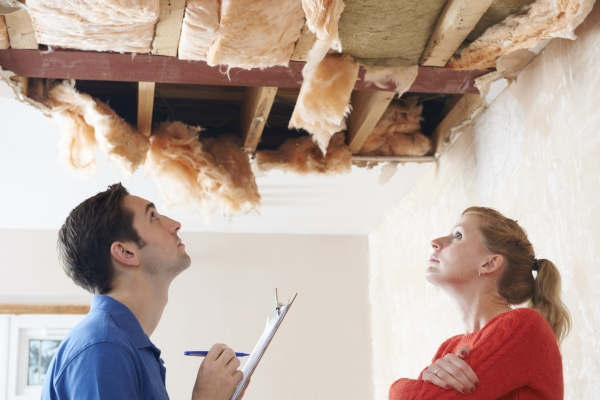 Male inspector and female client assessing interior roof damage.