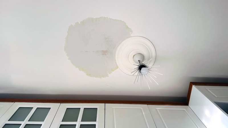 Photo of water leaking from a ceiling with visible water damage.